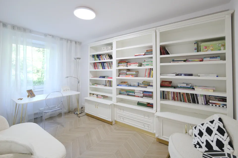 Biblioteka z białymi regałami i biurkiem przy oknie w domu przy Racławickiej 54 we Wrocławiu