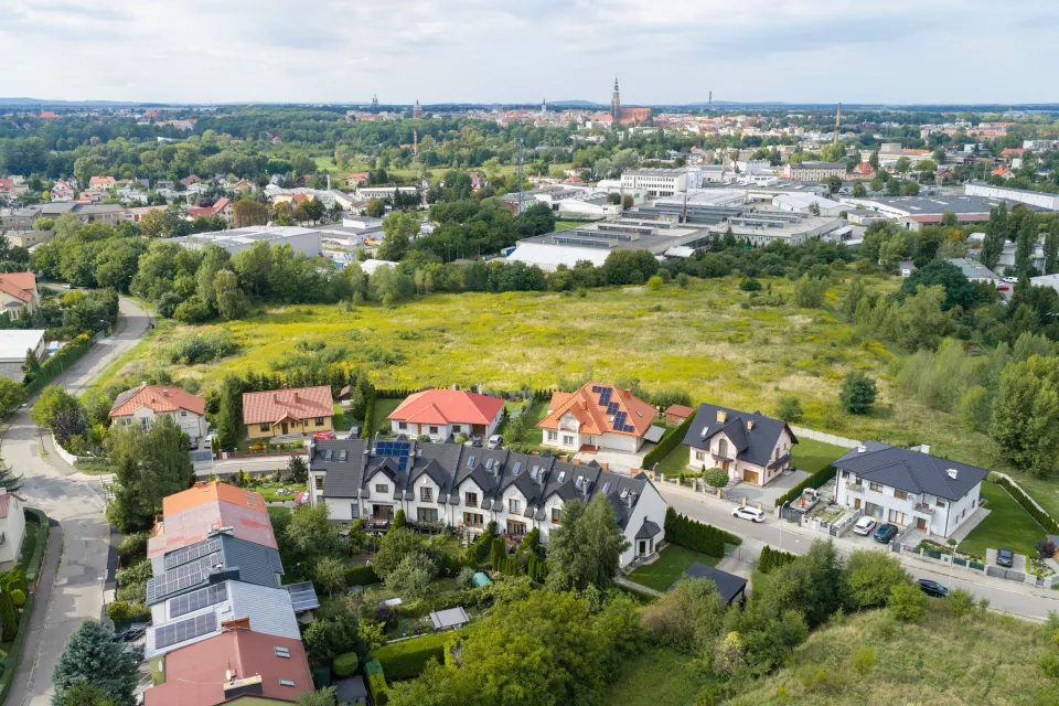Ujęcie lotnicze działki w Świdnicy z szeregowcami na pierwszym planie i panoramą miasta z wieżą kościoła w tle