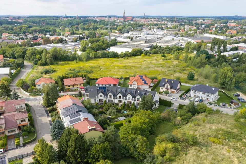 Działka w Świdnicy z powietrza — zielony teren, sąsiednia zabudowa jednorodzinna i zabudowania przemysłowe w oddali