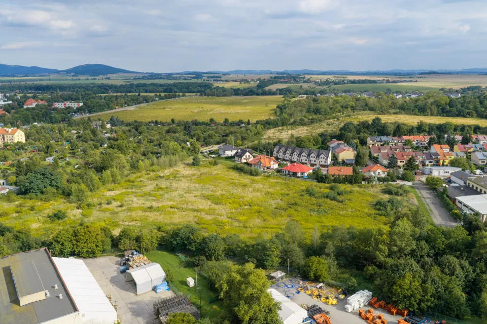 Szeroka perspektywa lotnicza działki w Świdnicy z polami, zadrzewieniem i pasmem wzgórz na horyzoncie